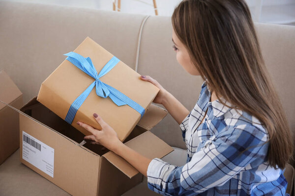 Young woman opening parcel at home