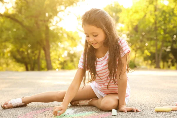 Sevimli küçük kız asfalt üzerinde açık havada tebeşir ile çizim