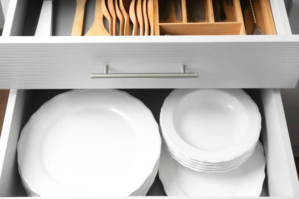 Set of ceramic plates in kitchen drawer, closeup