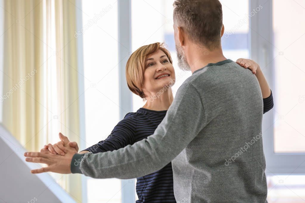 Happy mature couple dancing at home