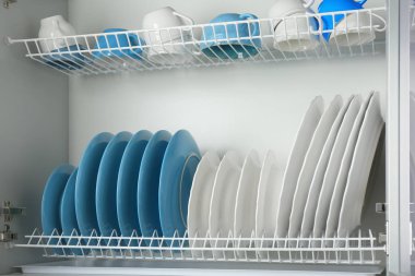Set of white and blue tableware on drying rack in kitchen clipart