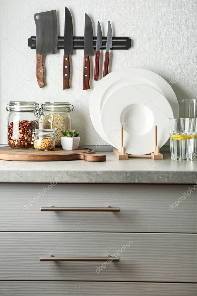 Kitchen counter with glass jars, knives and set of white plates