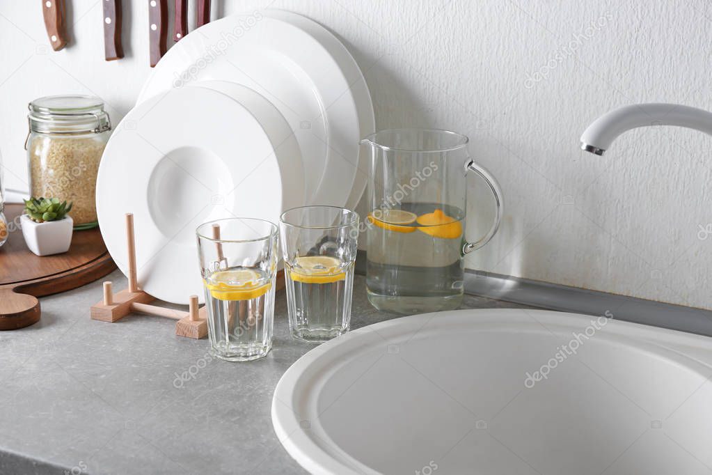 Set of white ceramic plates and fresh lemonade on kitchen counter