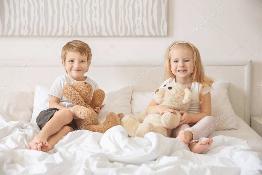 Cute children with toys on bed at home