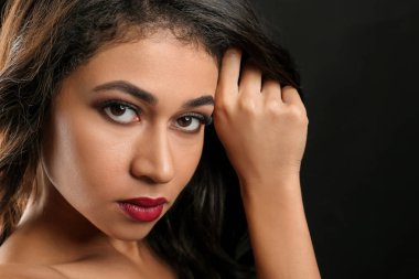 Siyah arka plan üzerine uzun kirpiklerini çekici Afrikalı-Amerikalı kadın. Kirpik uzantıları