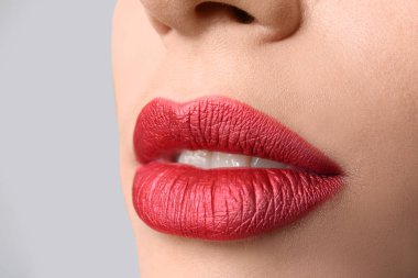 Gri arka plan, closeup parlak dudak makyaj ile genç kadın