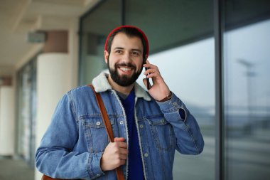 Cep telefonu açık havada üzerinde konuşurken yakışıklı trendy hipster