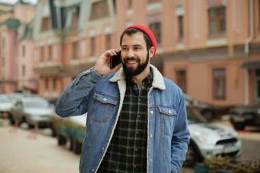 Cep telefonu açık havada üzerinde konuşurken yakışıklı trendy hipster