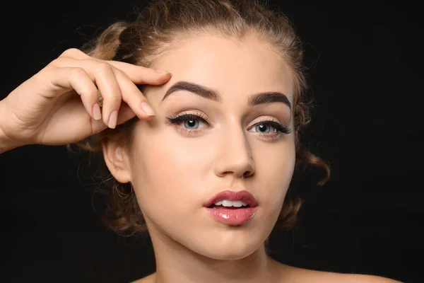 Young woman with beautiful eyebrows on dark background