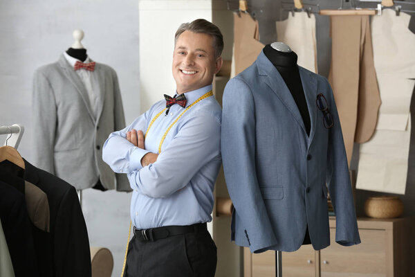 Tailor standing near mannequin with elegant jacket in atelier