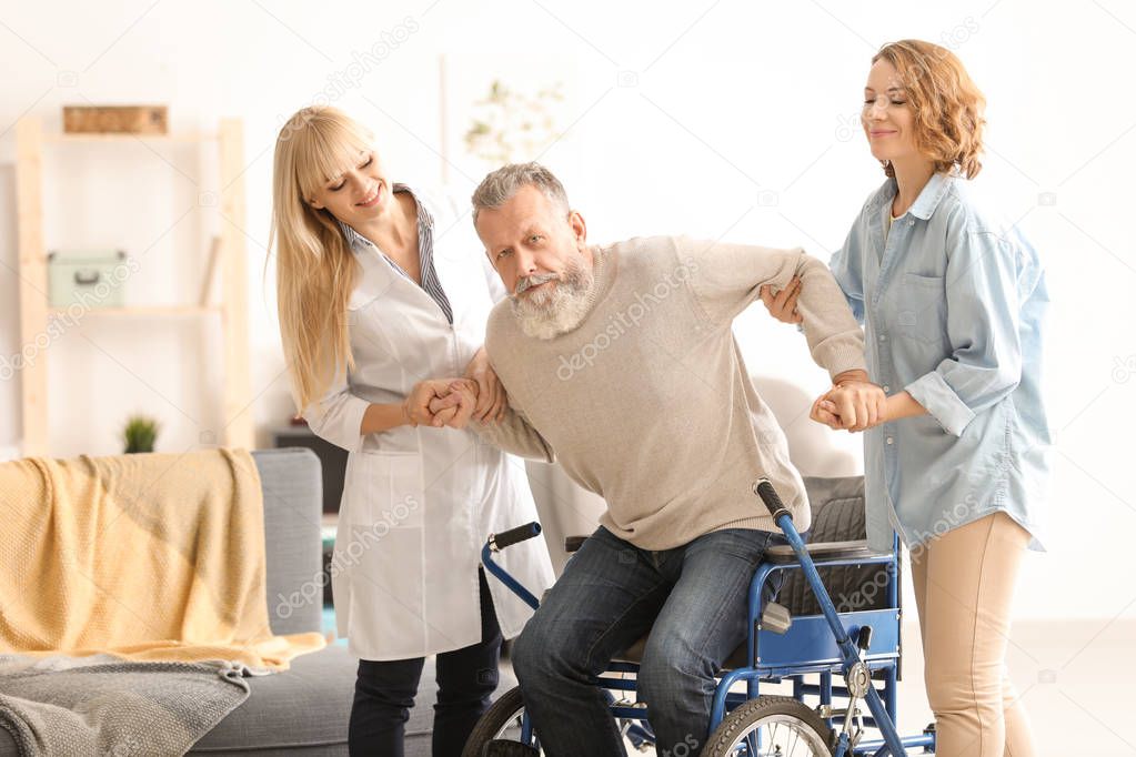 Young caregiver with senior man and his daughter at home