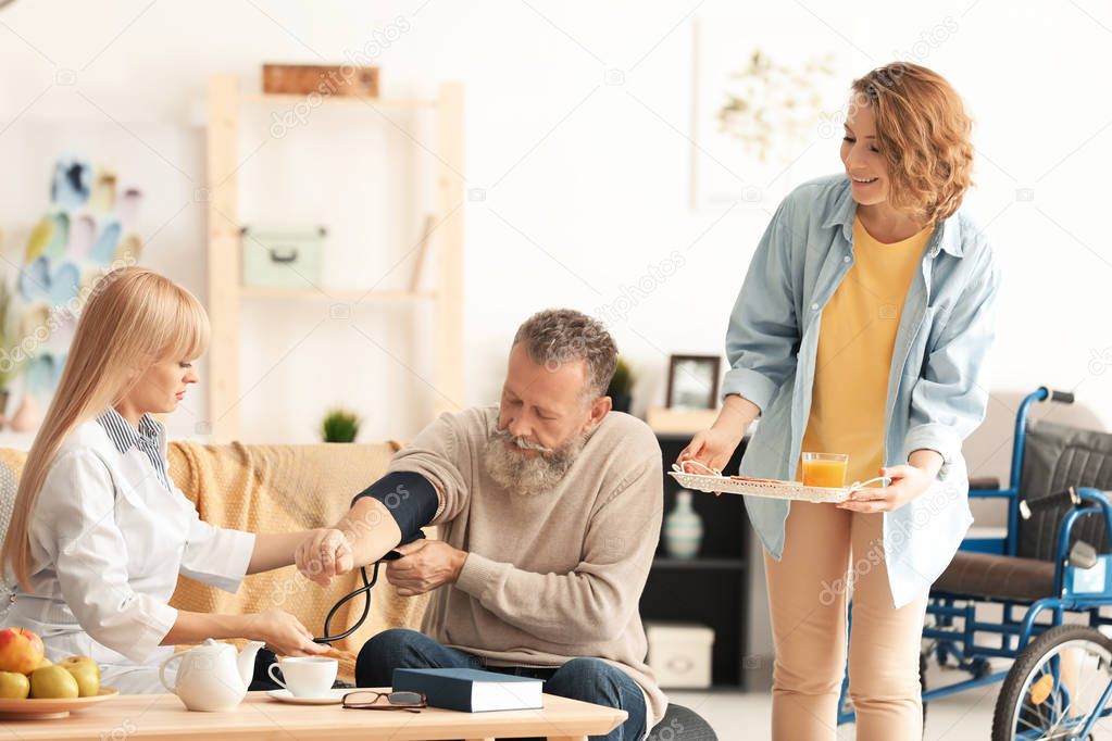 Young caregiver with senior man and his daughter at home