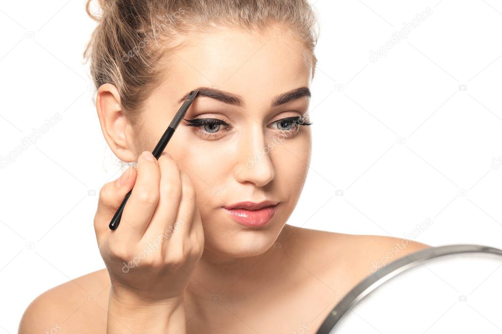 Young woman correcting shape of eyebrows on white background, closeup