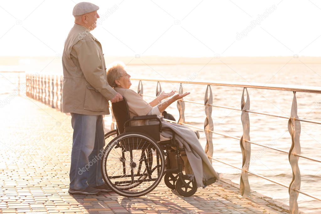 Senior woman in wheelchair with her friend from care home near river