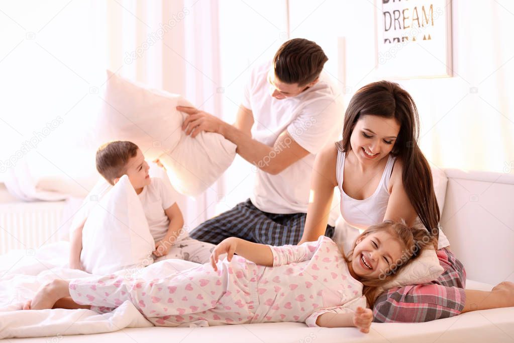 Happy family having pillow fight in bed at home
