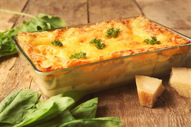 Ispanak ve ahşap zemin üzerine Parmesan peyniri ile lezzetli lazanya