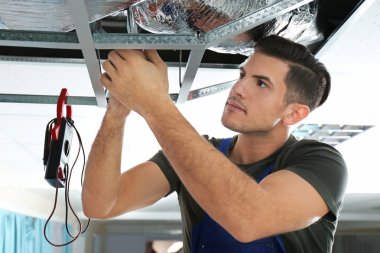 Male technician repairing industrial air conditioner indoors clipart