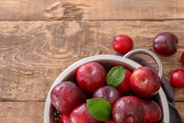 Kevgir ile ahşap masa üzerinde olgunlaşmış sulu Erik