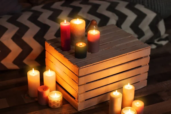 Burning candles and wooden crate indoors — Stock Photo, Image