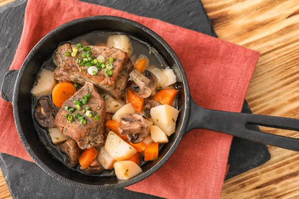 スレート皿の上の肉とジャガイモの煮込みとフライパン — ストック写真