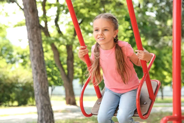 Linda niña jugando en columpios en el parque —  Fotos de Stock