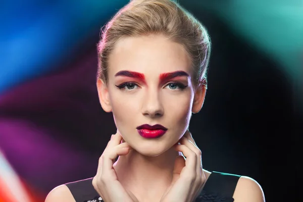 Ung kvinna med färgat ögonbrynen i färgglada projektorer lampor — Stockfoto