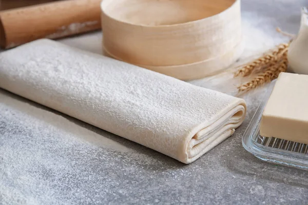 Raw flaky dough with flour on table — Stock Photo, Image