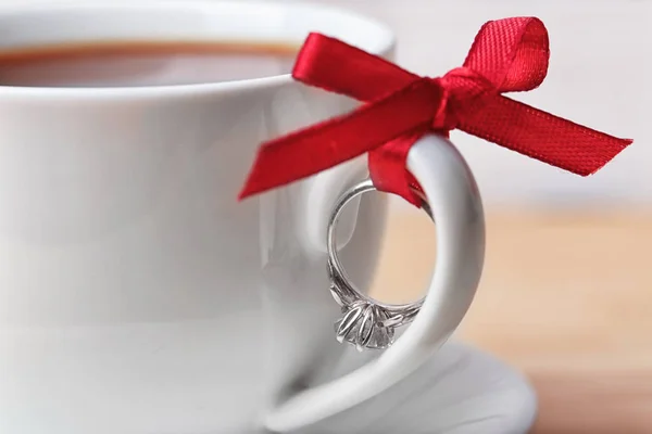 Engagement ring tied to cup of coffee, closeup — Stock Photo, Image