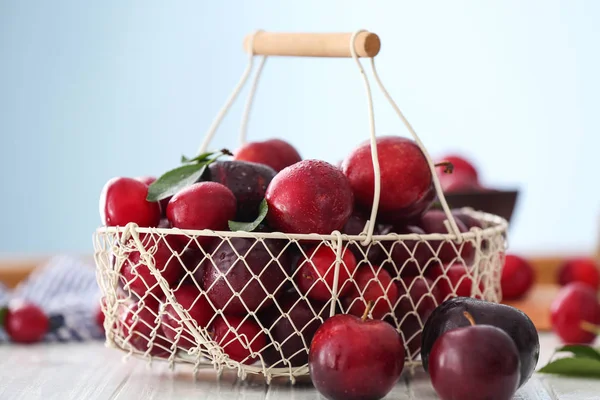 Metal basket with ripe juicy plums on table — Stock Photo, Image