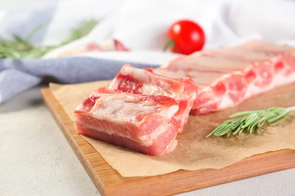 Placa de madeira com costelas cruas frescas na mesa — Fotografia de Stock