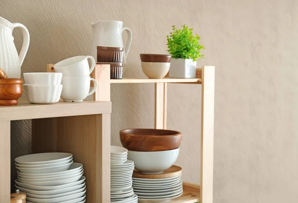 Soporte de almacenamiento con cerámica y utensilios de cocina de madera sobre fondo de color — Foto de Stock