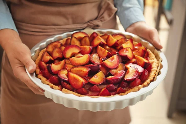 Woman holding delicious pie with plums, closeup — Stock Photo, Image