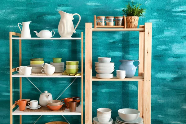 Kitchen shelving with dishes on color wall background — Stock Photo, Image