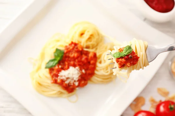 Delicious pasta with meat sauce on fork over plate — Stock Photo, Image