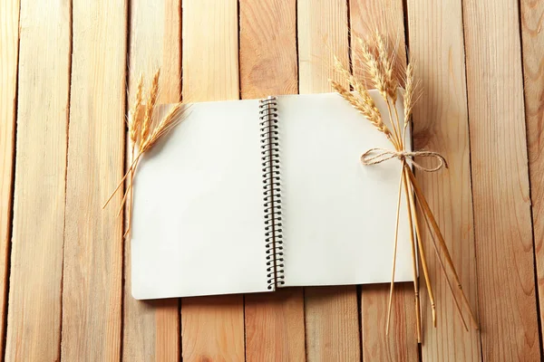 Cuaderno y espigas de trigo sobre fondo de madera. Hacer pan casero —  Fotos de Stock