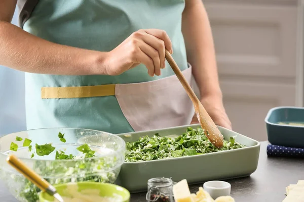 Mujer cocinando lasaña de espinacas en la cocina —  Fotos de Stock