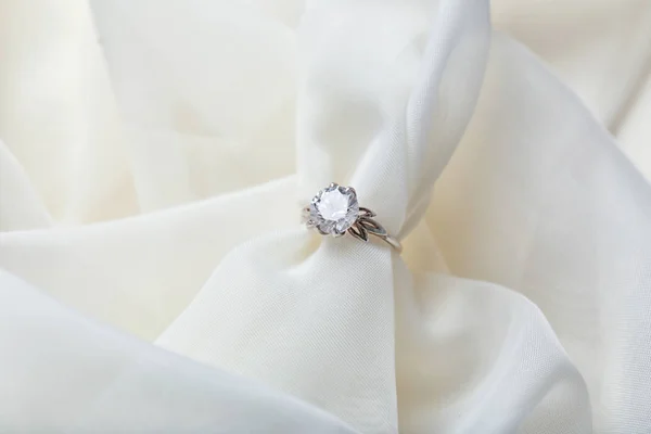 Beautiful engagement ring on light fabric, closeup