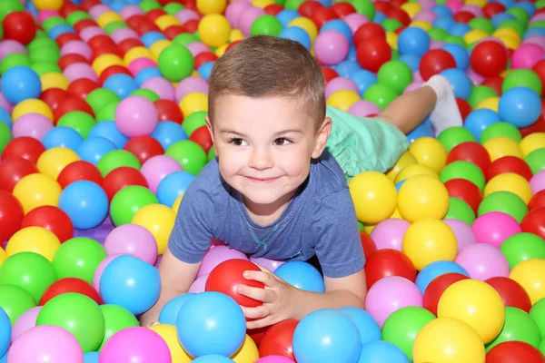 Bonito menino jogando entre bolas de plástico — Fotografia de Stock