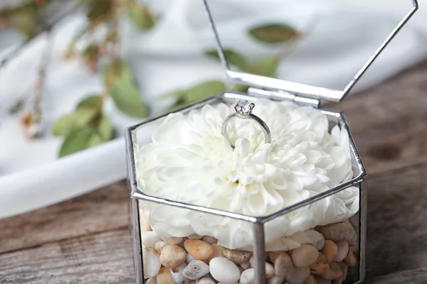 Anel de noivado bonito com flor em caixa de vidro na mesa — Fotografia de Stock