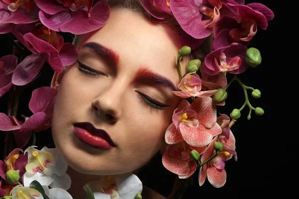 Young woman with dyed eyebrows surrounded by flowers — Stock Photo, Image