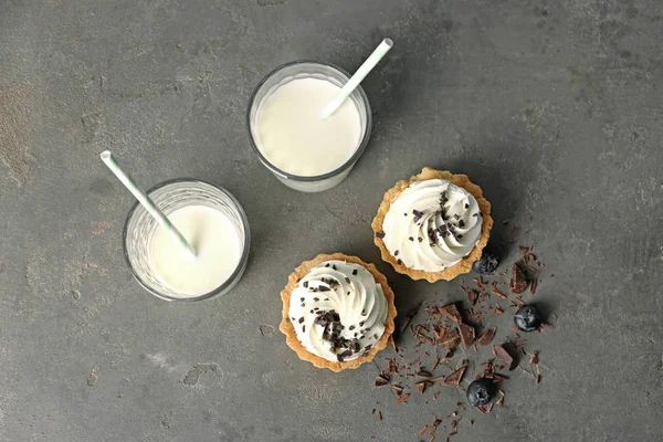 Tasty tartlets with whipped cream and milk on grey background — Stock Photo, Image