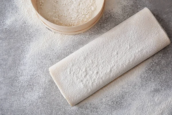 Raw flaky dough with flour on table — Stock Photo, Image