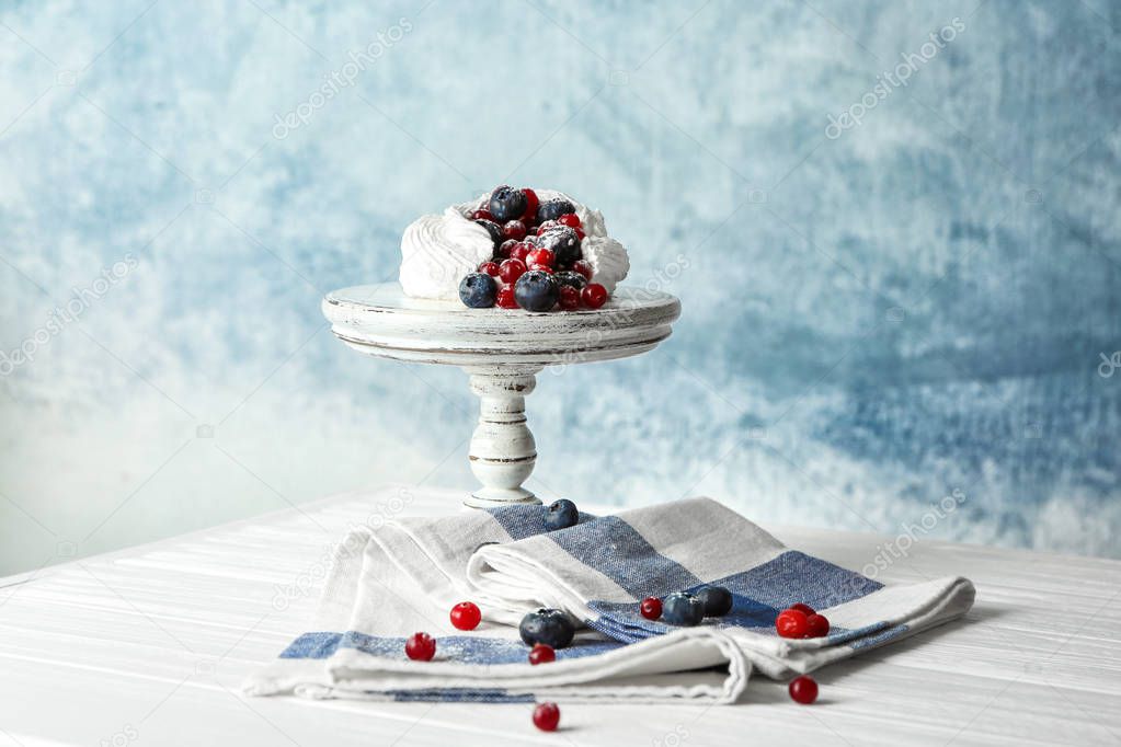 Stand with tasty Pavlova cake on table