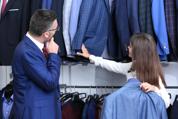 Unga shop assistent hjälpa mannen att välja kostym i butik — Stockfoto