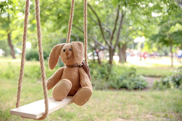 Bunny toy left on swings in park — Stock Photo, Image