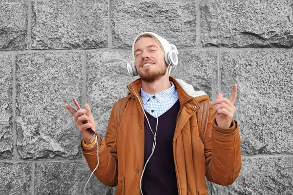 Retrato de hipster guapo con auriculares escuchando música al aire libre —  Fotos de Stock