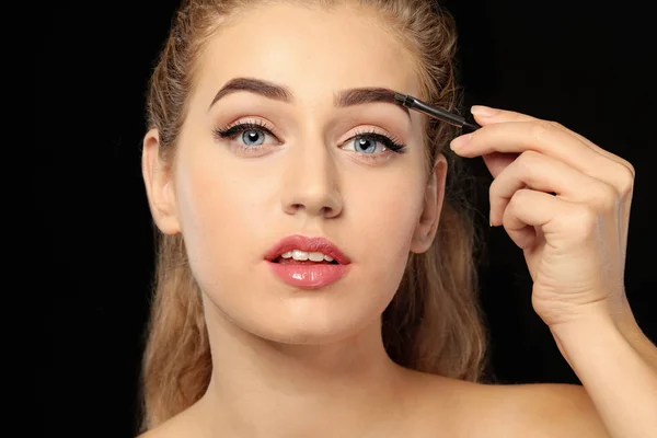 Junge Frau Korrigiert Augenbrauenform Auf Dunklem Hintergrund Nahaufnahme — Stockfoto