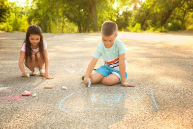 Sevimli küçük çocuklar asfalt üzerinde açık havada tebeşir ile çizim