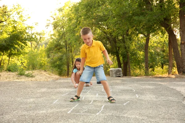 Lindos niños pequeños jugando hopscotch, al aire libre —  Fotos de Stock