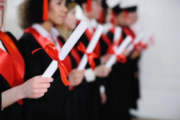 Hallgatók főiskolai köpenyt a zárt oklevelek. Diplomaszerzés nap — Stock Fotó